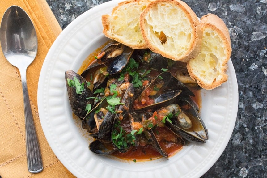 Mussels with Tomatoes & White Wine with Garlic Toasts in a white bowl