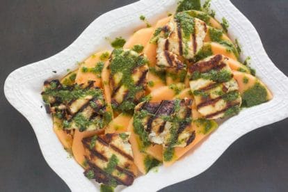 overhead image of grilled halloumi salad with melon on rectangular white platter