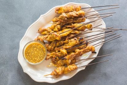 Singapore chicken satay on oval white platter with dipping sauce