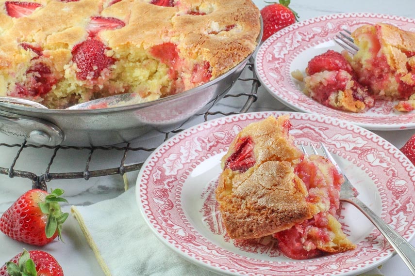 strawberry skillet cake on pink and white plate with silver fork; skillet in background