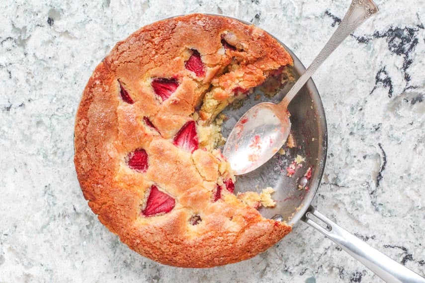 strawberry yogurt skillet cake in pan on quartz counter with a silver serving spoon