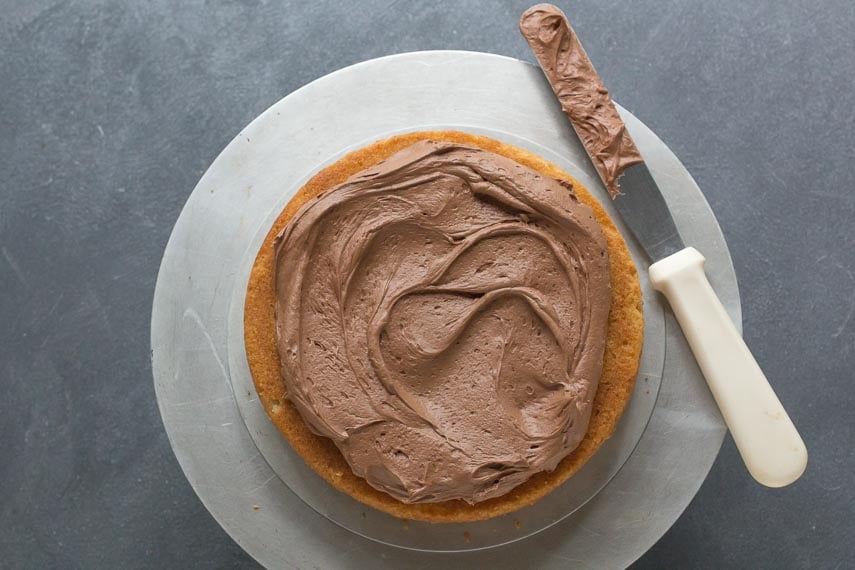 applying low FODMAP chocolate frosting to a yellow cake