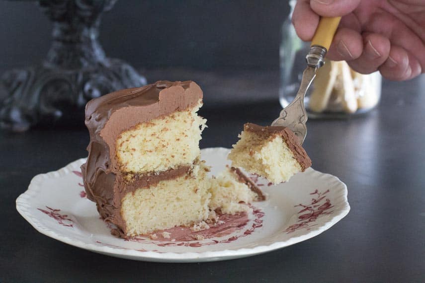 low FODMAP yellow cake with chocolate frosting being eaten with a fork