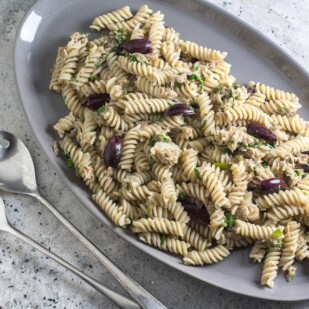 Low FODMAP Pantry Pasta with Tuna, Lemon & Olives on a gray platter with serving spoons