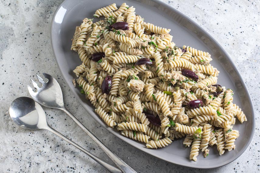 Low FODMAP Pantry Pasta with Tuna, Lemon & Olives on a gray platter with serving spoons