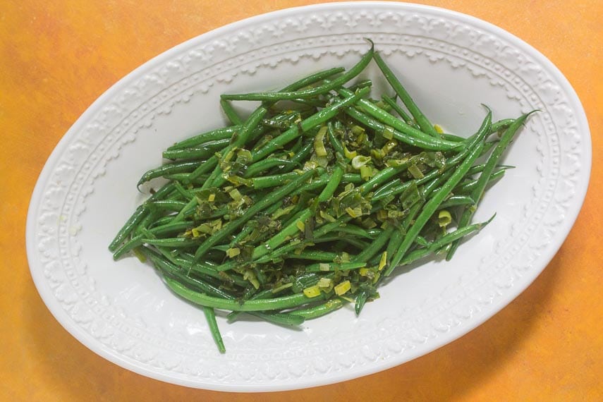 Low FODMAP Triple “Onion” Green Beans on a white bowl against a deep yellow background
