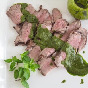overhead image of Grilled Butterflied Leg of Lamb with Mint Salsa Verde on square white platter