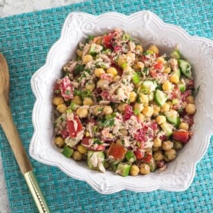 overhead image of Low FODMAP Mediterranean Tuna Salad with Chickpeas on aqua placemat with wooden spoon alongside