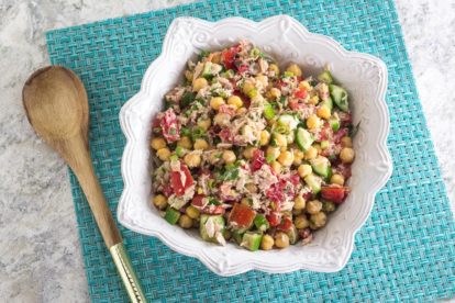 overhead image of Low FODMAP Mediterranean Tuna Salad with Chickpeas on aqua placemat with wooden spoon alongside