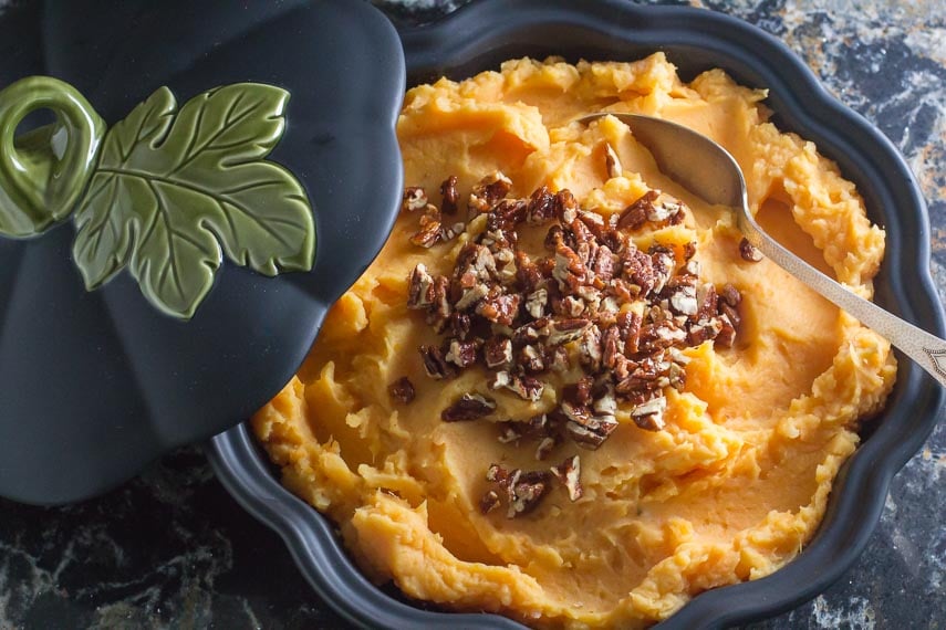 Low FODMAP Mashed Sweet Potatoes with Candied Spiced Pecans in a dark casserole dish