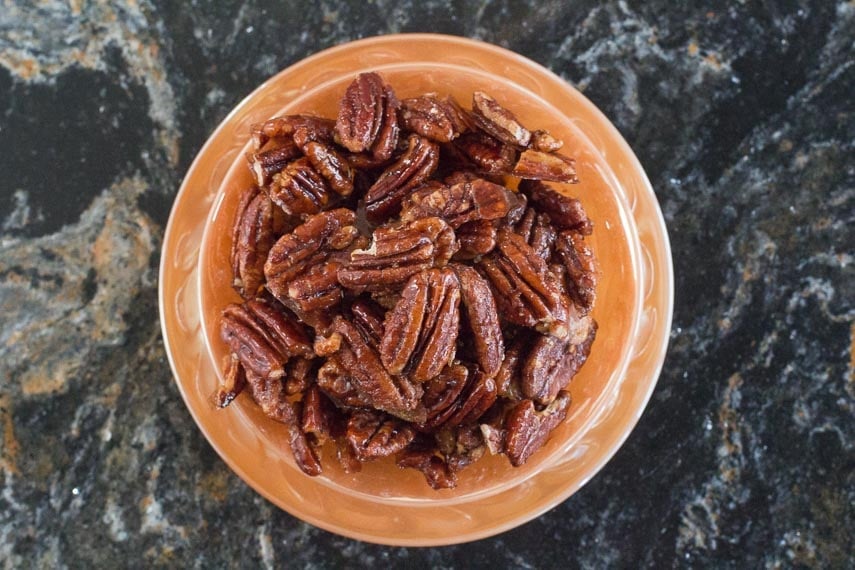 overhead of Low FODMAP Candied Spiced Pecans in orange colored dish