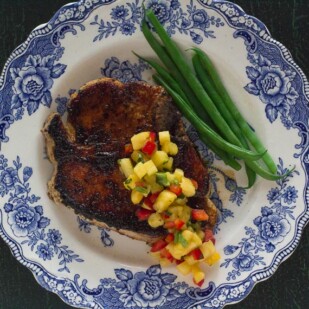 pork chop with low FODMAP Sweet & Spicy Dry Rub and low FODMAP Pineapple Salsa with green beans on a blue and white plate