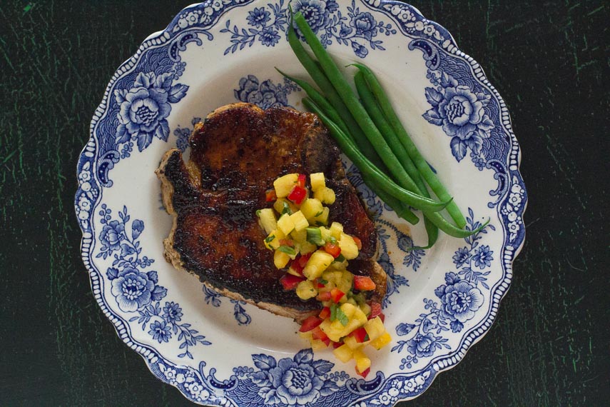 pork chop with low FODMAP Sweet & Spicy Dry Rub and low FODMAP Pineapple Salsa with green beans on a blue and white plate