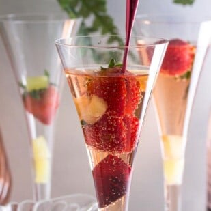 Low FODMAP Pineapple Strawberry Prosecco in champagne glass with red stirrer