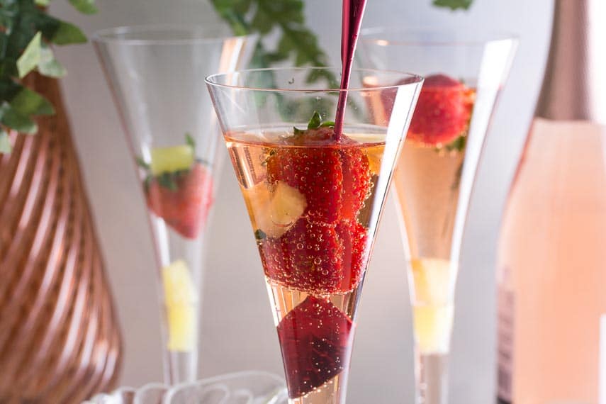 Low FODMAP Pineapple Strawberry Prosecco in champagne glass with red stirrer