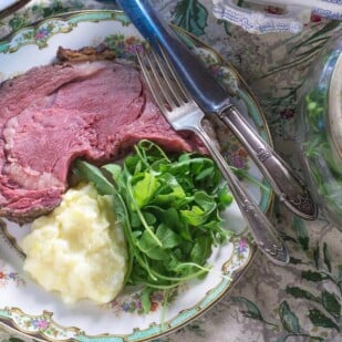 Low FODMAP Standing Rib Roast with a Dijon Herb Crust plated with arugula salad and mashed potatoes