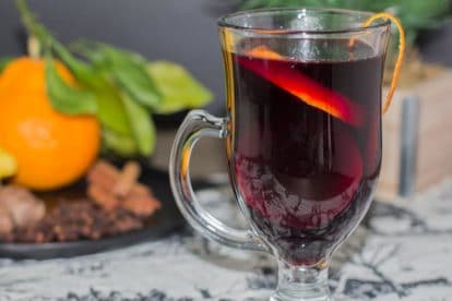 closeup of low fodmap mulled wine with orange zest on rim of clear glass mug