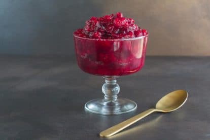 Low FODMAP horseradish cranberry sauce with gold spoon in glasss footed dish