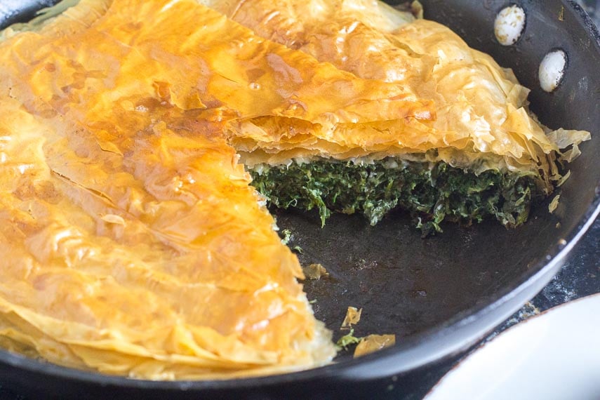 low FODMAP Spanakopita Spinach Pie in baking pan with wedge removed