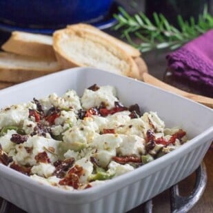low fodmap baked feta with olives and sundried tomatoes with toasted baguette in background