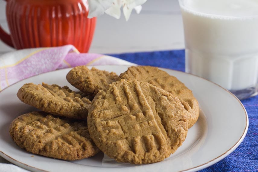 one bowl peanut butter cookies on a white plate with glass of lactose-free milk