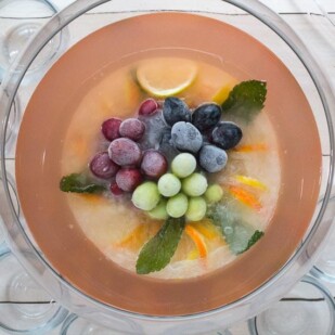 overhead image of Low FODMAP Fruited Lemonade Rosé Punch with punch cups and ladle