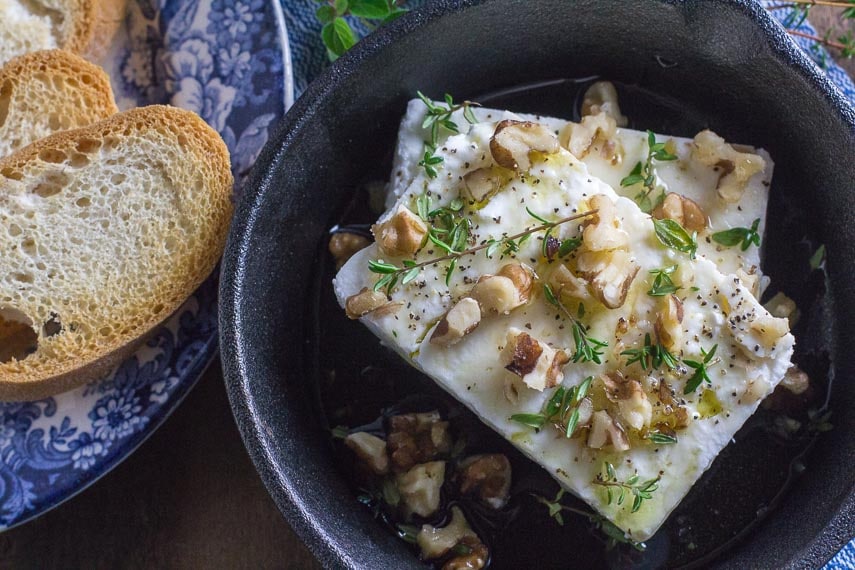 overhead image of baked feta with honey and walnuts and thyme in a cast-iron pan