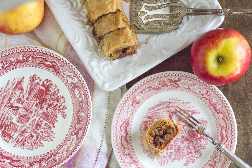 overhead image of low FODMAP apple strudel on red and white plate with apples in background