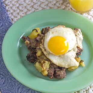 overhead of roast beef hash with fried egg and blue napkin