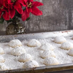 pecan butterballs on a baking sheet pan covered with confectioners' sugar
