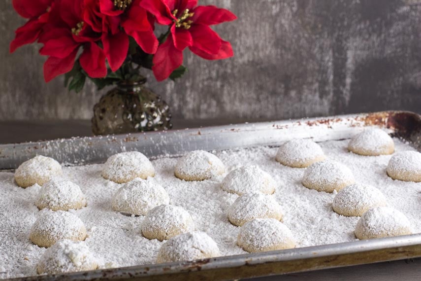 pecan butterballs on a baking sheet pan covered with confectioners' sugar