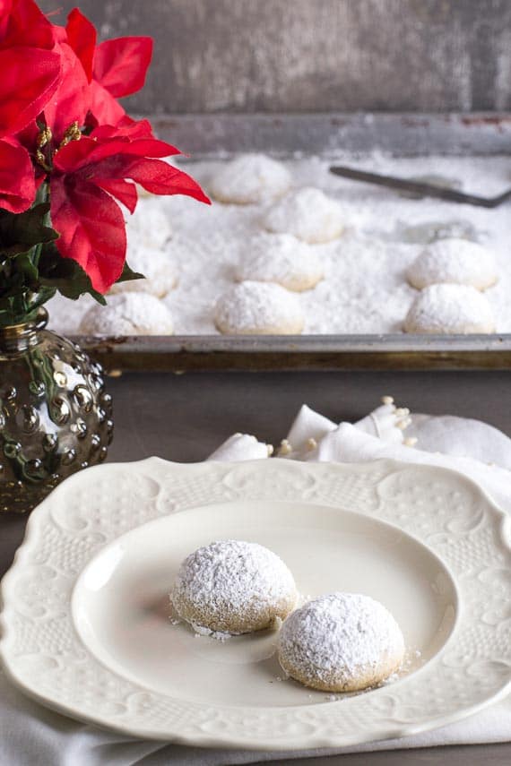 vertical image of pecan butterballs cookies on a white plate