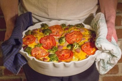 forrester holding savory bread pudding in white oval casserole