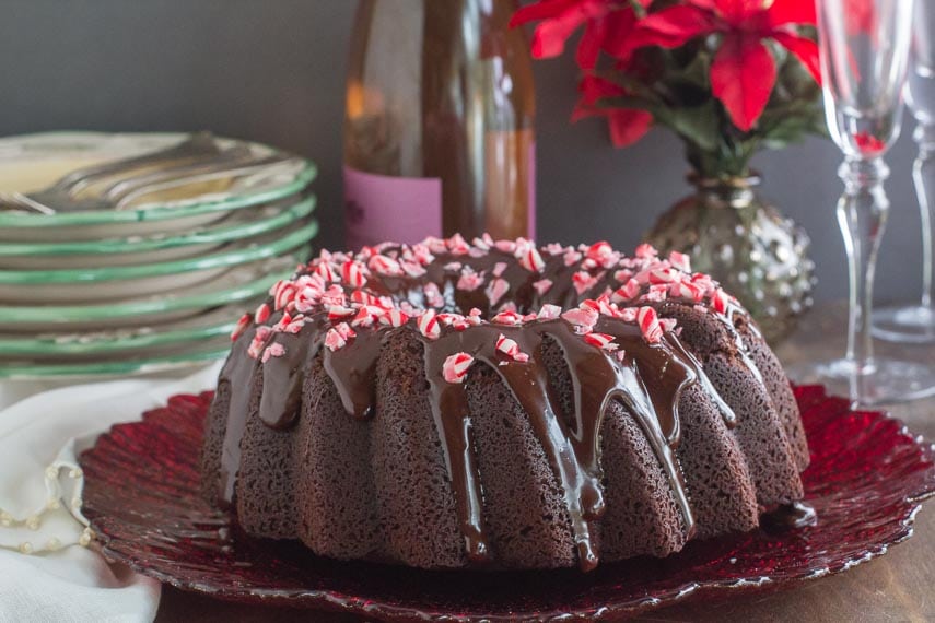 horizontal image of low FODMAP Chocolate Peppermint Cake on a red plate with plates and glasses in background
