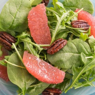 Greens with Grapefruit and Candied pecans on a blue glass plate