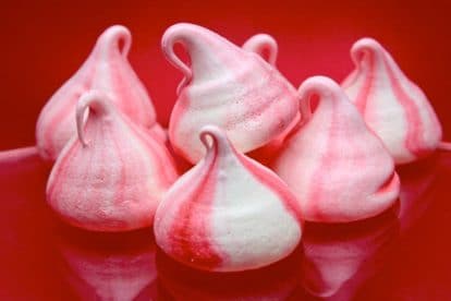 Low FODMAP Peppermint Meringues piped as kisses on red background