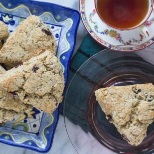 low FODMAP vegan scones piled on a platter and on a pink glass plate with a cup of tea