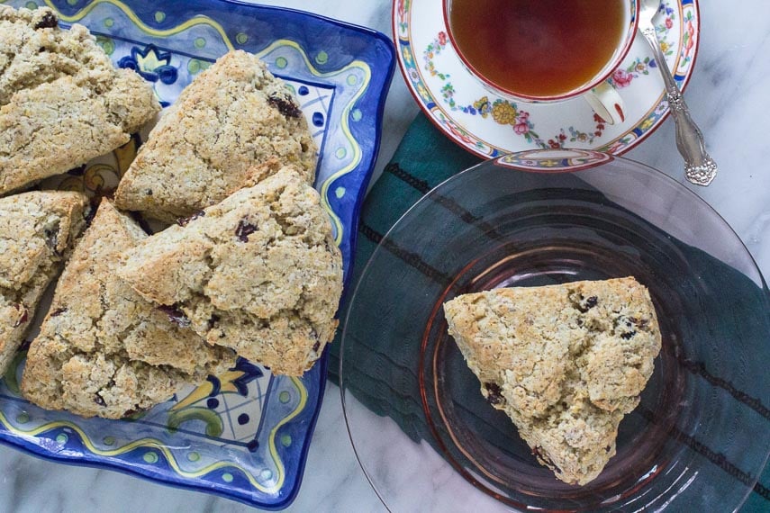 low FODMAP vegan scones piled on a platter and on a pink glass plate with a cup of tea