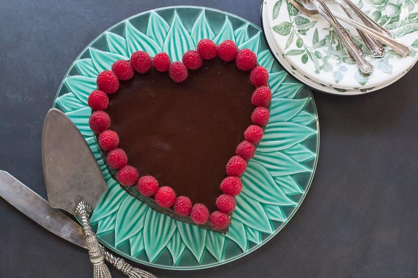 overhead view of low FODMAP Raspberry Chocolate Truffle Cake on green platter with plates