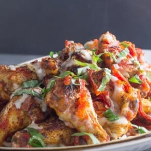 pile of low FODMAP pizza chicken wings on white plate with steam