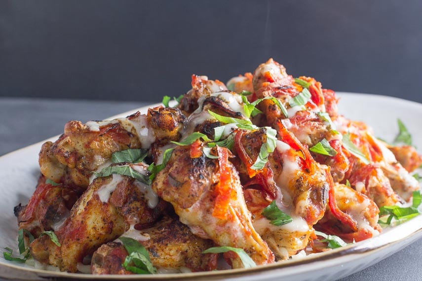 pile of low FODMAP pizza chicken wings on white plate with steam