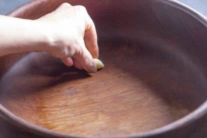 rubbing garlic on wooden salad bowl