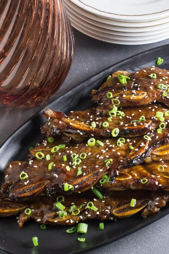 vertical image of low FODMAP Korean BBQ Short Ribs with scallions and sesame seeds on dark background