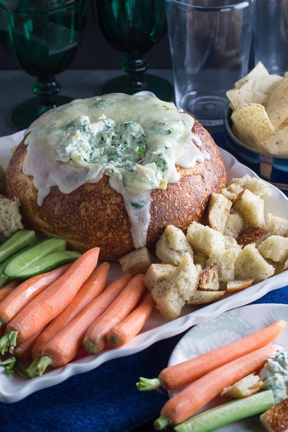 vertical image of low FODMAP hot spinach artichoke dip in a bread bowl