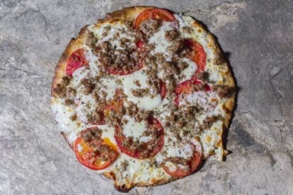 Low FODMAP CBD Oil Pizza with Sausage & Fresh Tomato on a stone surface