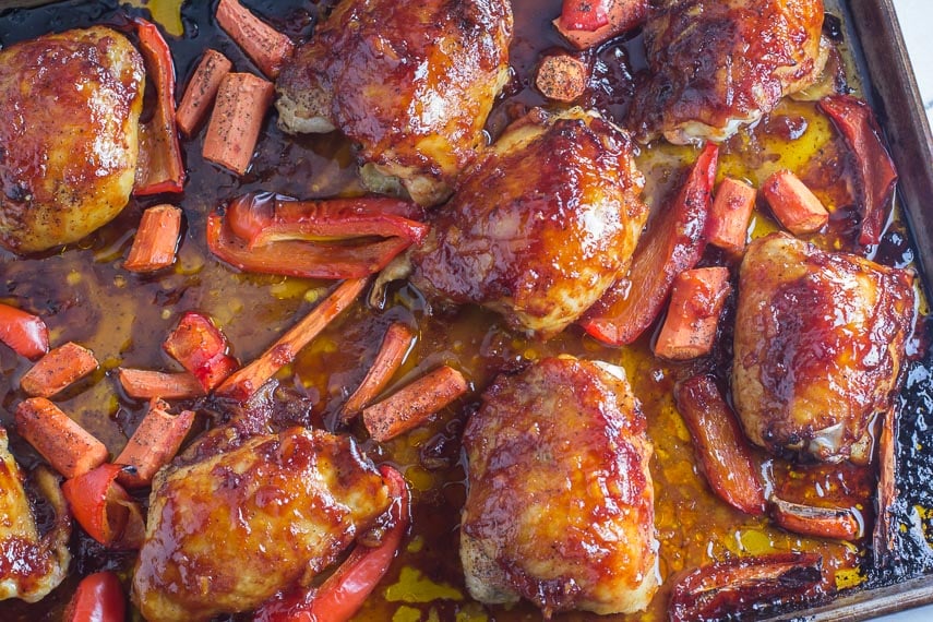 Low FODMAP Orange marmalade BBQ Sauce brushed on chicken, carrots and red bell peppers in a roasting pan