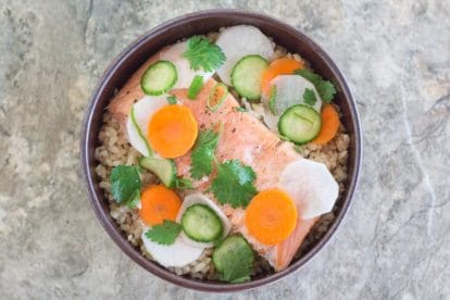 Low FODMAP Salmon Brown Rice Nourish Bowl with Quick Pickles on a stone surface
