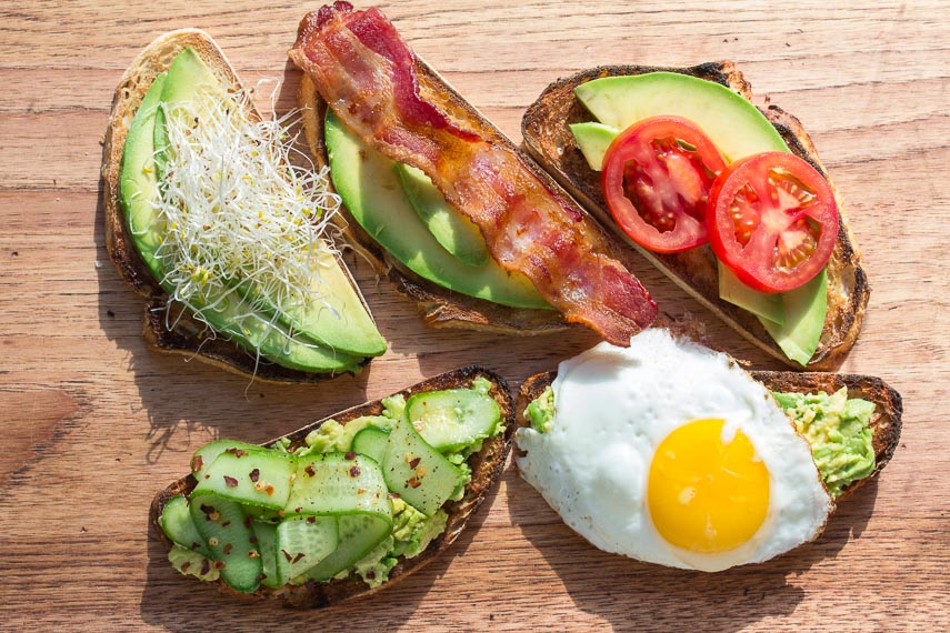 assorted low FODMAP avocado toast on a wooden board - great for breakfast, lunch or a snack