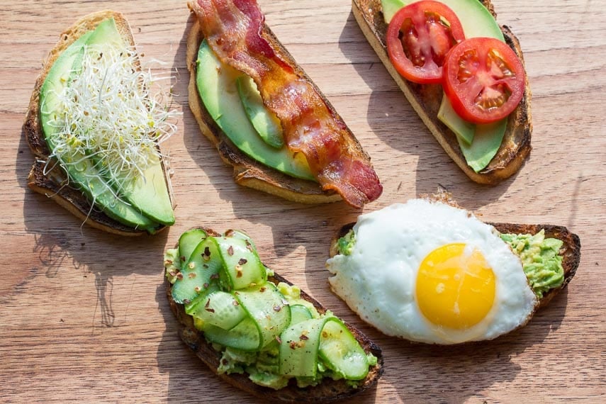 assorted low FODMAP avocado toast on a wooden board