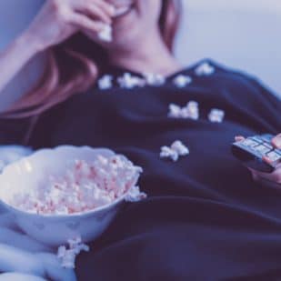 woman eating popcorn in bed